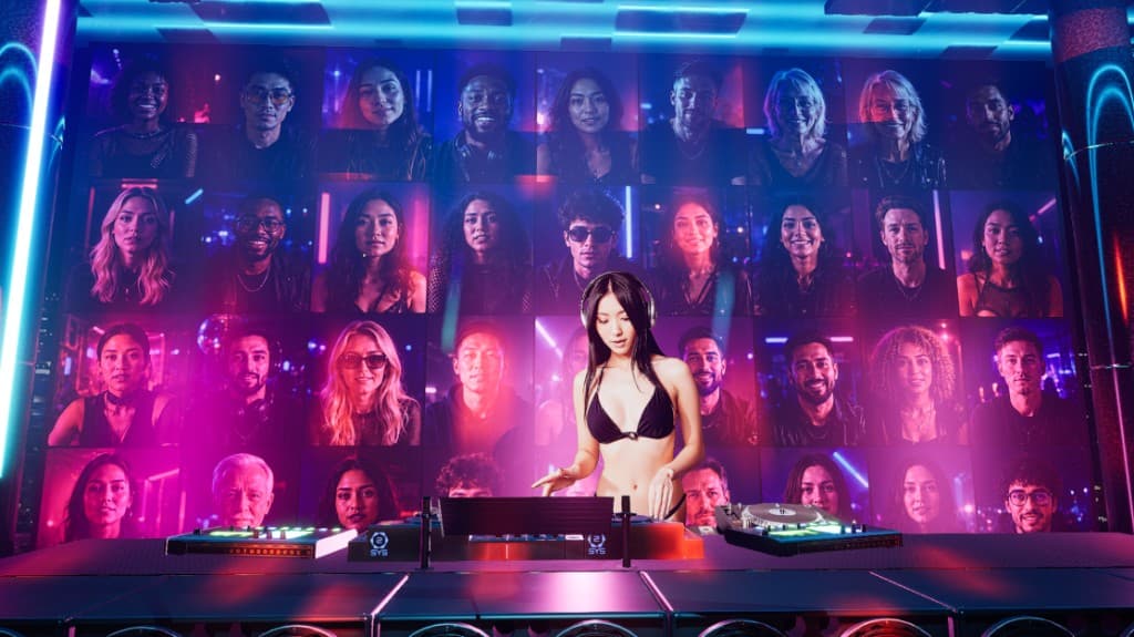DJ performing with audience video wall of fan cams behind